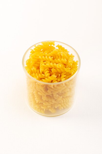 Un canestro di vista frontale con pasta gialla italiana asciutta della pasta dentro la ciotola di plastica trasparente sul bianco