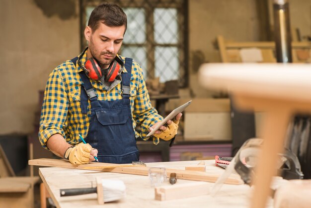 Un carpentiere maschio che utilizza compressa digitale nell&#39;officina