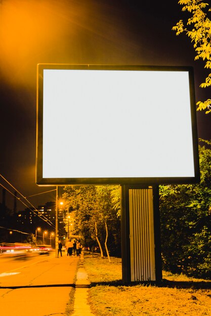 Un cartellone bianco sul ciglio della strada della città di notte