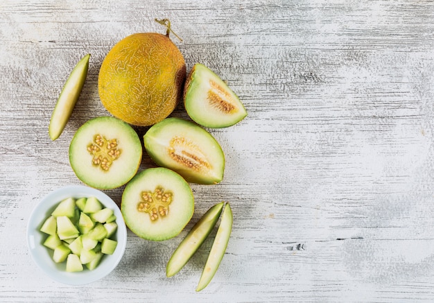 Un certo melone affettato con il melone in ciotola su fondo di pietra bianco, vista superiore. copia spazio per il testo