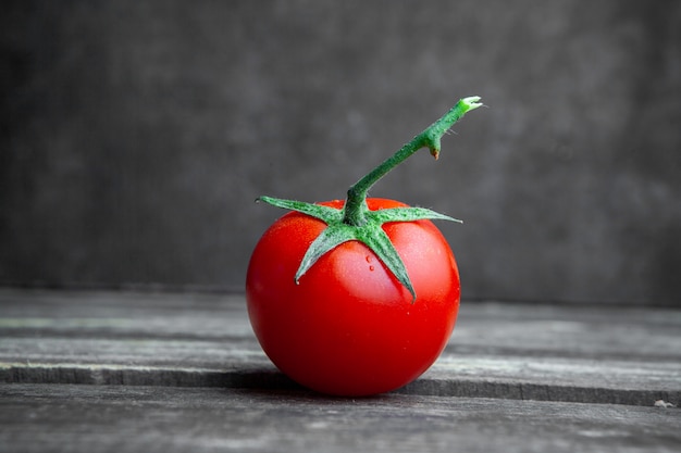 Un certo pomodoro su fondo di legno e strutturato scuro, vista laterale.