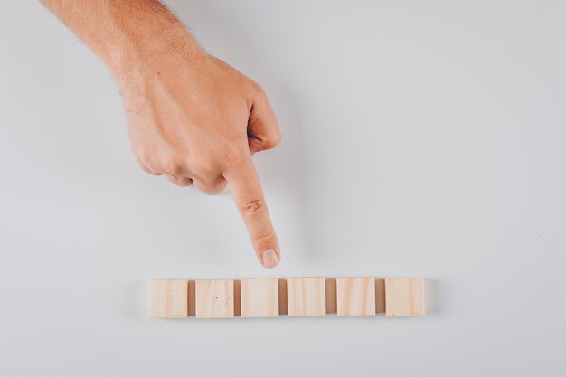 Un certo uomo che indica i blocchi di legno su bianco