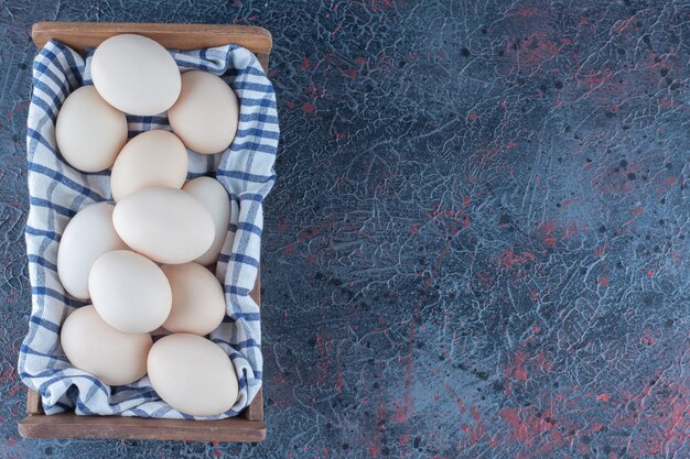 Un cestino di legno con uova di gallina crude fresche.