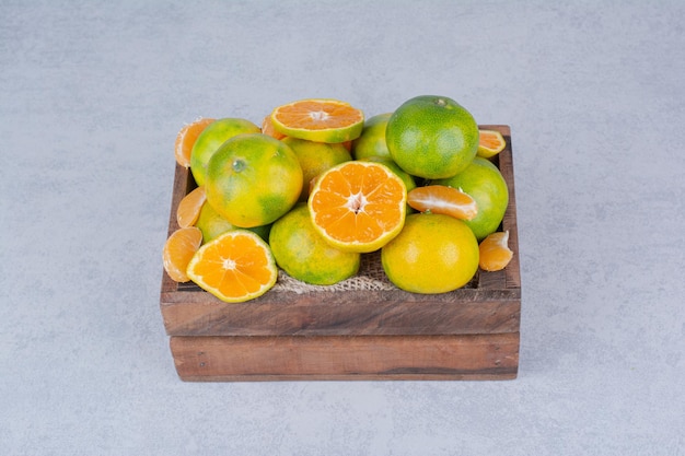 Un cesto di legno pieno di mandarini a fette su sfondo bianco. Foto di alta qualità