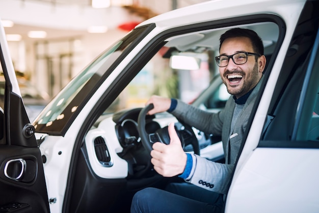 Un cliente soddisfatto e felice ha appena acquistato un'auto nuova di zecca presso il concessionario di veicoli