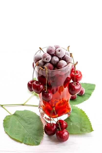 Un cocktail della ciliegia di vista frontale con il raffreddamento del ghiaccio delle ciliege rosse fresche su bianco, colore della frutta del cocktail della spremuta della bevanda