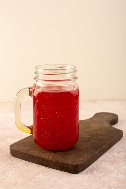 Un cocktail rosso ciliegia vista frontale all'interno di poco può raffreddamento fresco sullo scrittorio di legno e rosa