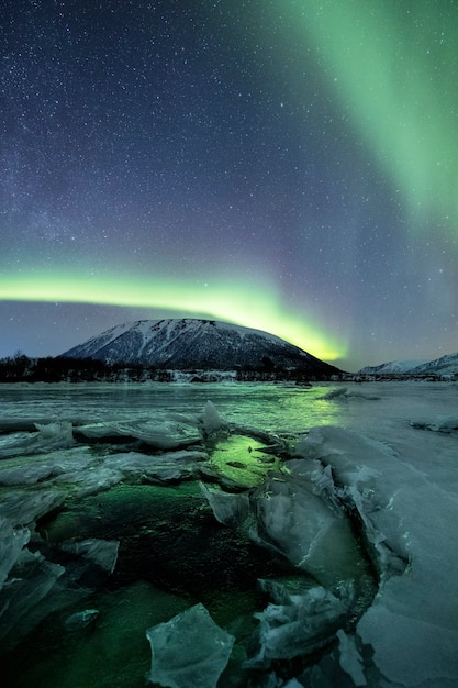 Un colpo verticale di montagne innevate sotto una luce polare