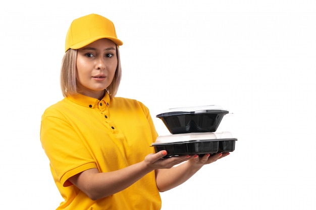 Un corriere femminile di vista frontale in ciotole gialle della tenuta del cappuccio giallo della camicia con alimento su bianco
