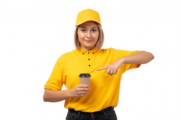 Un corriere femminile di vista frontale in protezione gialla della camicia gialla e jeans neri che sorride tenendo la tazza di caffè su bianco