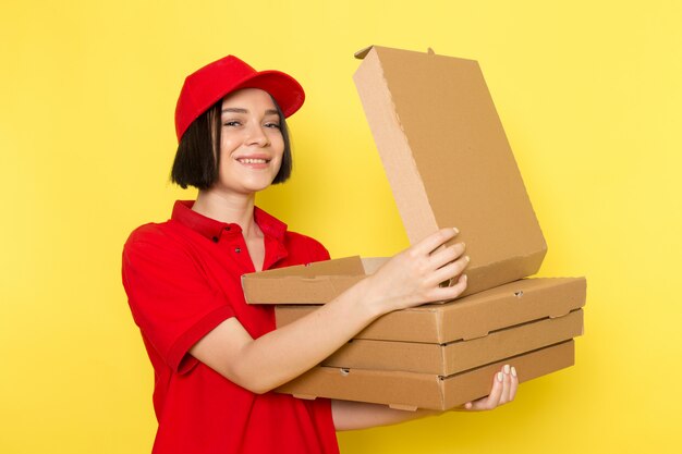 Un corriere femminile giovane di vista frontale in guanti neri uniformi rossi e spiritello malevolo che tengono le scatole di alimento