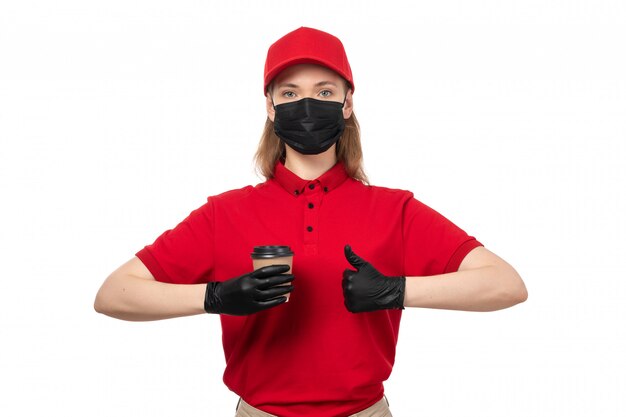 Un corriere femminile vista frontale in berretto rosso camicia rossa e maschera nera che tiene tazza di caffè