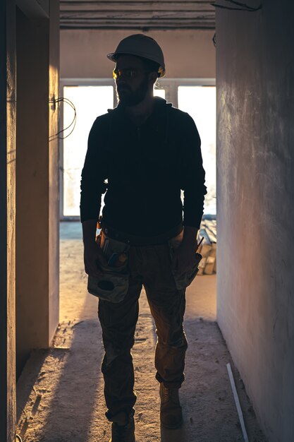 Un costruttore maschio in abiti da lavoro con un casco protettivo in un cantiere in piena crescita.