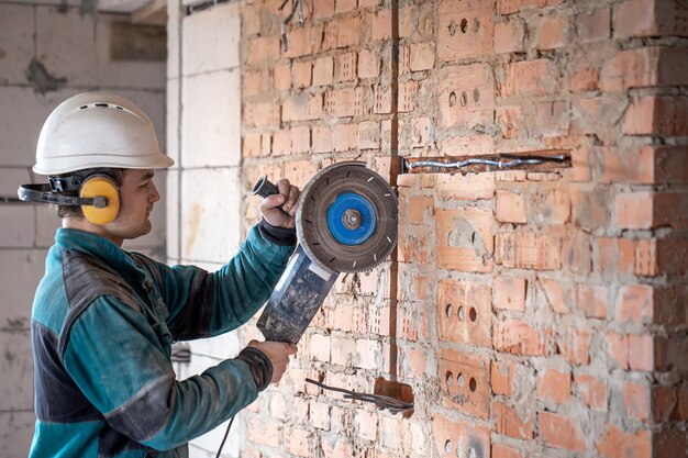 Un costruttore professionista in abiti da lavoro lavora con uno strumento di taglio.