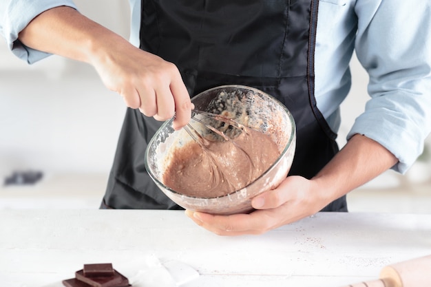 Un cuoco con uova su una cucina rustica sullo sfondo delle mani degli uomini