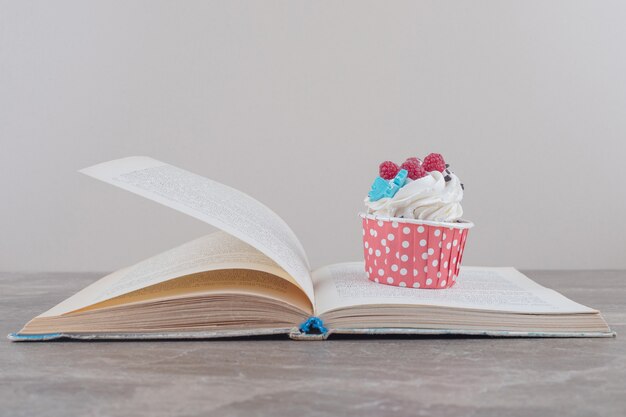 Un cupcake e un libro aperto su marmo