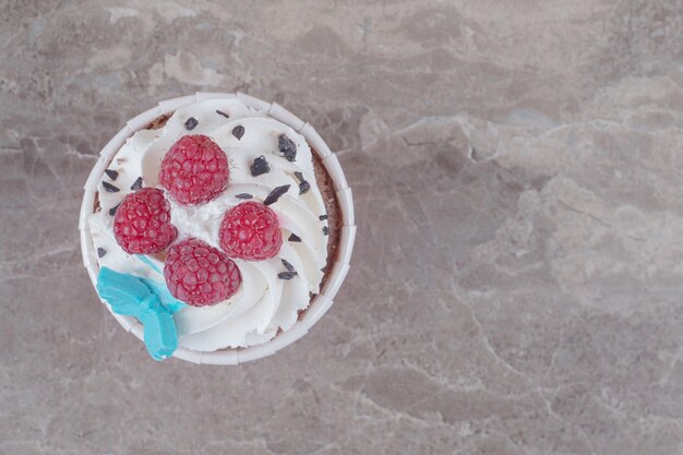 Un cupcake ricoperto di crema e frutti di bosco su marmo