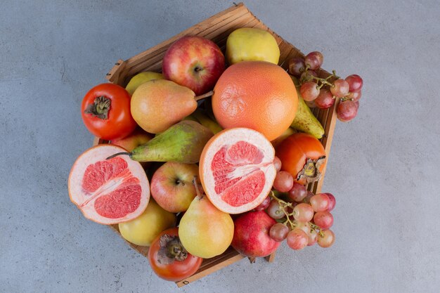 Un delizioso assortimento di frutta in un cesto di legno su sfondo di marmo.
