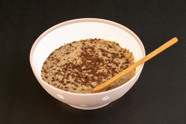 Un dolce delizioso saporito del dessert choco marrone di vista frontale con caffè in polvere dentro il piatto bianco isolato sui dessert di rinfresco dolci del fondo scuro