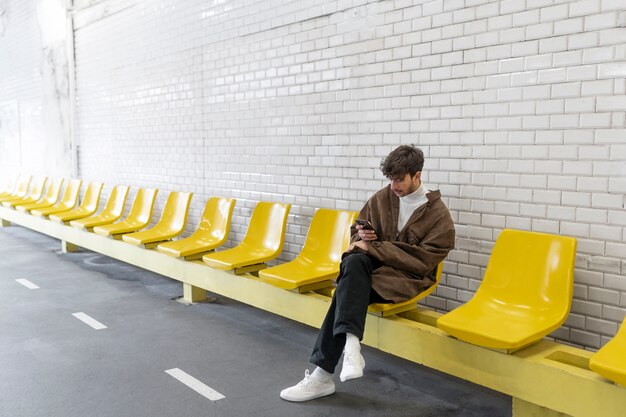 Un francese che aspetta il treno della metropolitana e usa il suo smartphone
