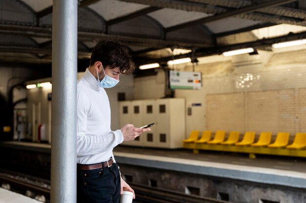 Un francese che aspetta il treno della metropolitana e usa il suo smartphone