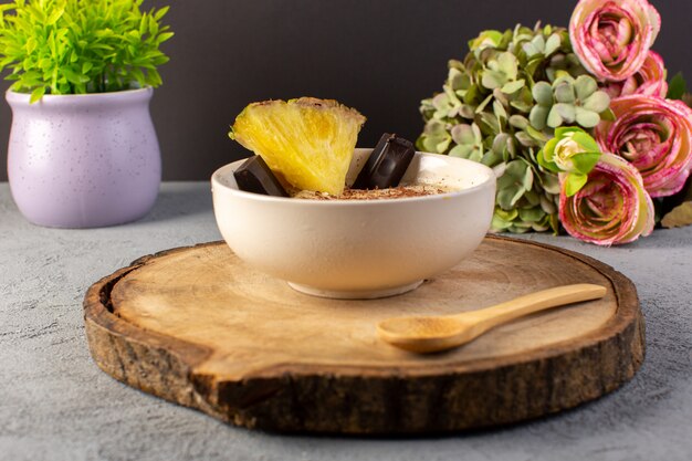 Un fronte chiuso vista choco dessert marrone con fetta di ananas choco bar fiori sulla scrivania in legno marrone e grigio