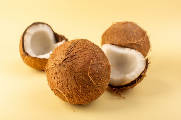 Un fronte fresco chiuso latteo fresco di noci di cocco vista frontale isolato isolato sul dado tropicale esotico della frutta del fondo color crema