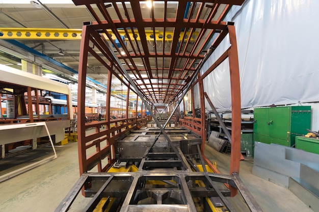 Un giorno lavorativo di moderna produzione di auto filobus per autobus automatici con auto non finite lavoratori in uniforme protettiva in background automobilistico braccio di saldatura della linea di assemblaggio di automobili