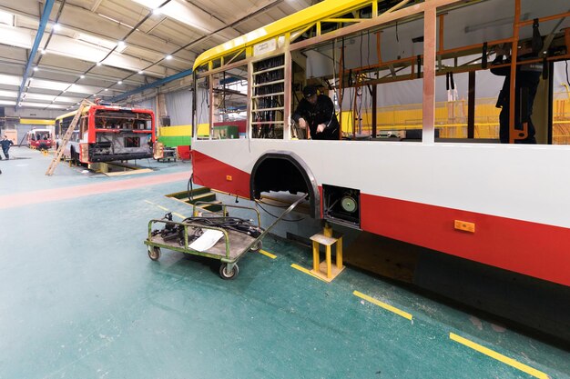 Un giorno lavorativo di moderna produzione di autobus automatici con lavoratori di automobili non finiti nell'industria automobilistica di uniformi protettive