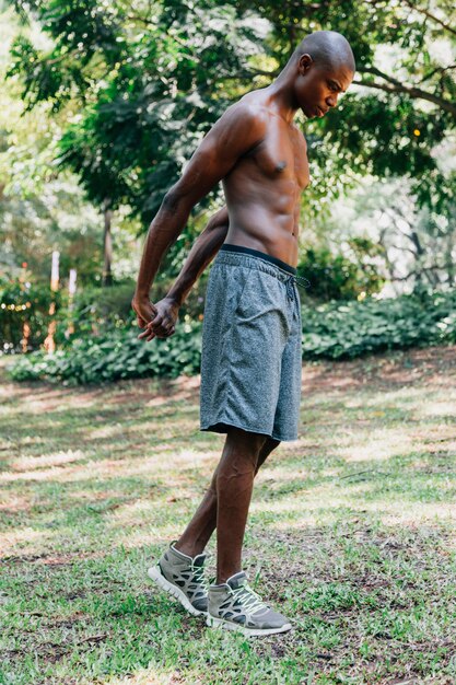 Un giovane atleta di sesso maschile in pantaloncini che si estende la mano nel parco