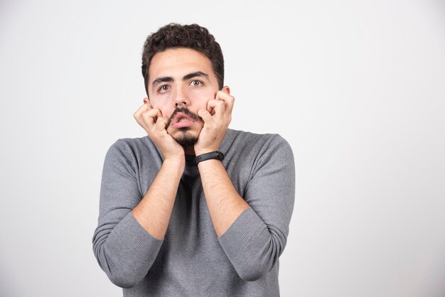 Un giovane che fa una faccia buffa su un muro bianco.