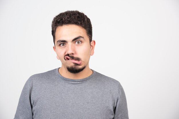 Un giovane che fa una faccia buffa su un muro bianco.