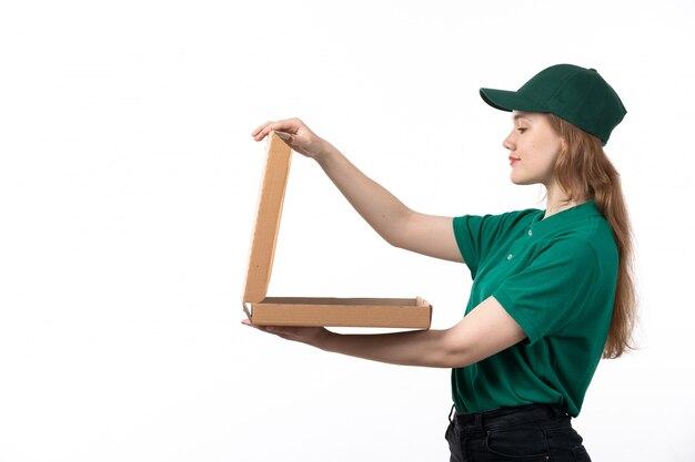 Un giovane corriere femminile di vista frontale in scatole di cibo sorridenti uniformi verdi della tenuta che lo aprono vuoto