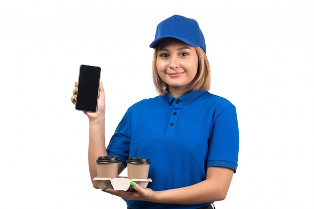 Un giovane corriere femminile di vista frontale in tazze blu del telefono e di caffè della tenuta dell'uniforme