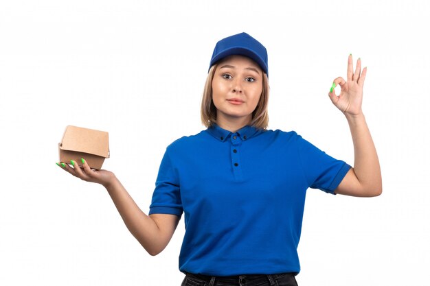 Un giovane corriere femminile di vista frontale in uniforme blu che tiene il pacchetto di consegna dell'alimento