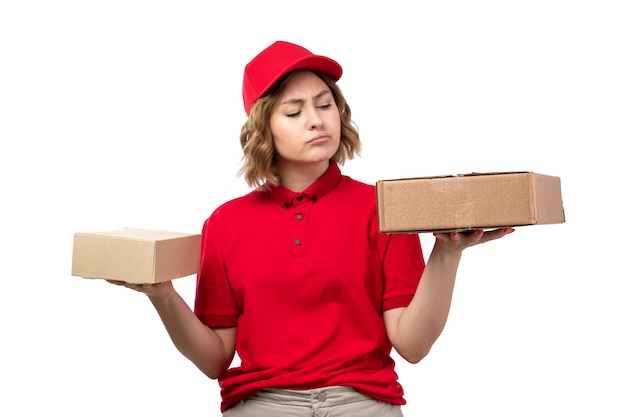 Un giovane corriere femminile di vista frontale nei pacchetti di consegna della tenuta del cappuccio rosso della camicia rossa