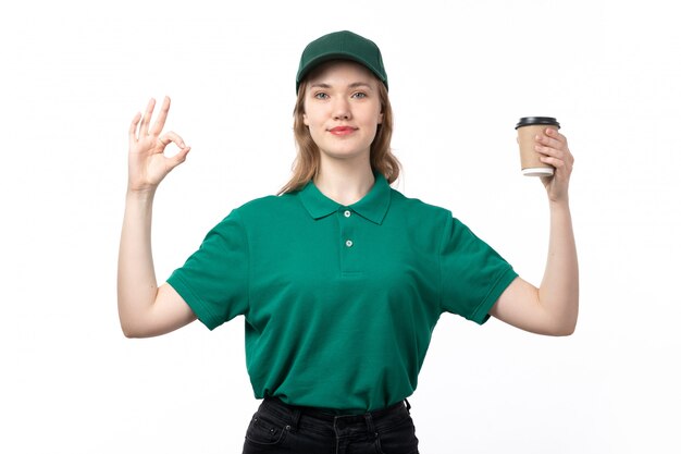 Un giovane corriere femminile di vista frontale nel bianco della tazza di caffè e del smilingon della tenuta dell'uniforme di verde