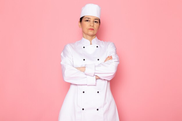 Un giovane cuoco femminile di vista frontale in protezione bianca del vestito del cuoco bianco che propone sguardo serio dispiaciuto
