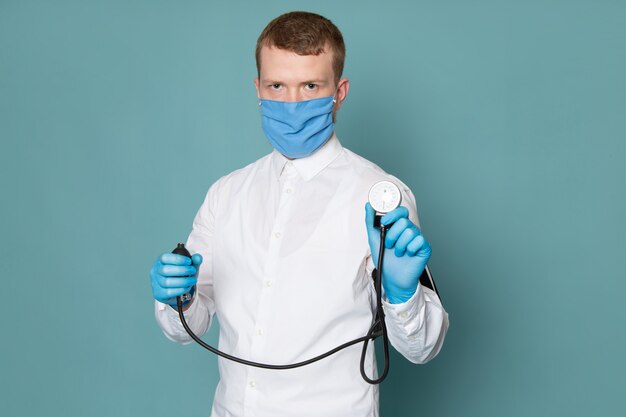 Un giovane di vista frontale in camicia bianca e guanti blu con maschera sullo spazio blu