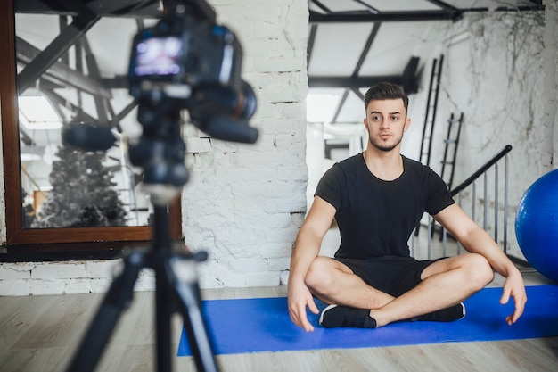 Un giovane e bellissimo blogger di fitness scrive video per il suo blog e racconta le regole base durante un allenamento, in una stanza in stile loft