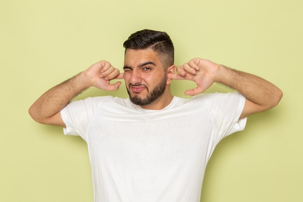 Un giovane maschio di vista frontale in maglietta bianca che copre le sue orecchie