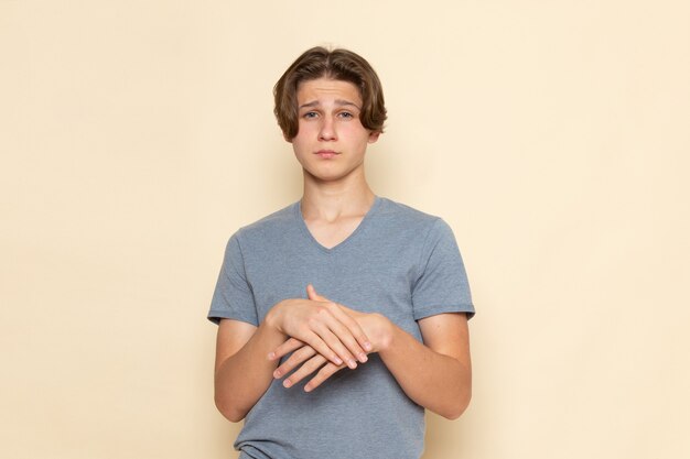 Un giovane maschio di vista frontale in maglietta grigia che posa con l'espressione di pensiero