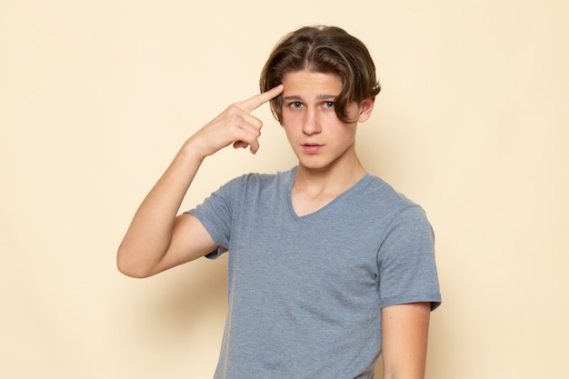 Un giovane maschio di vista frontale nella posa grigia della maglietta