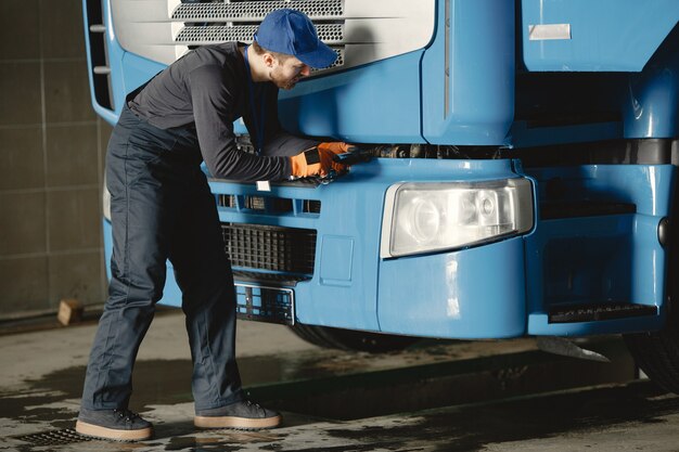 Un giovane operaio controlla la ruota. Malfunzionamento del camion. Lavoro di servizio.