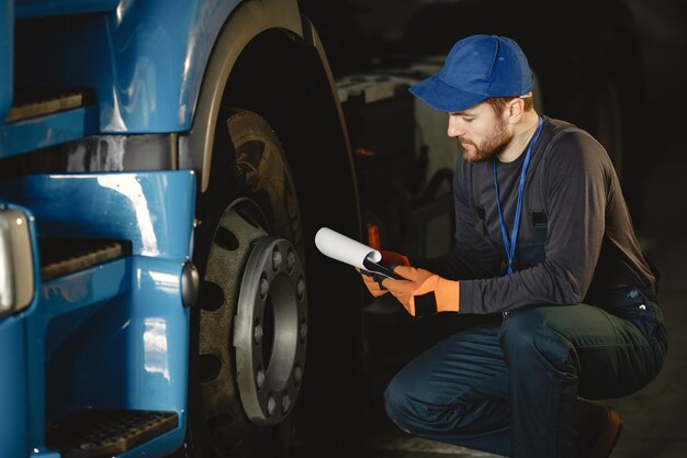 Un giovane operaio controlla la ruota. Malfunzionamento del camion. Lavoro di servizio.