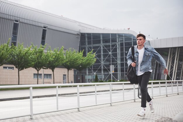 Un giovane uomo bello all'aeroporto sta aspettando il volo.