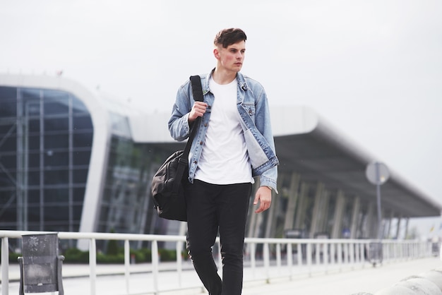 Un giovane uomo bello all'aeroporto sta aspettando il volo.