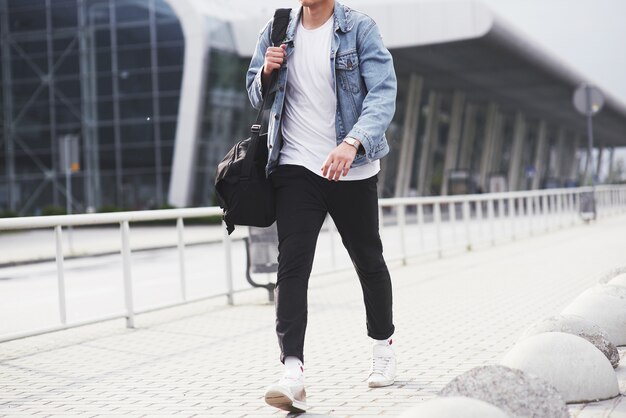 Un giovane uomo bello all'aeroporto sta aspettando il volo.