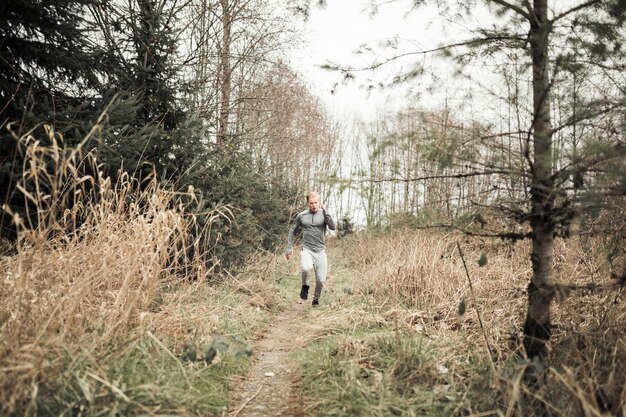 Un giovane uomo che corre sul sentiero attraverso la foresta