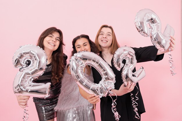 Un gruppo di amiche con palloncini d'argento a forma di numeri
